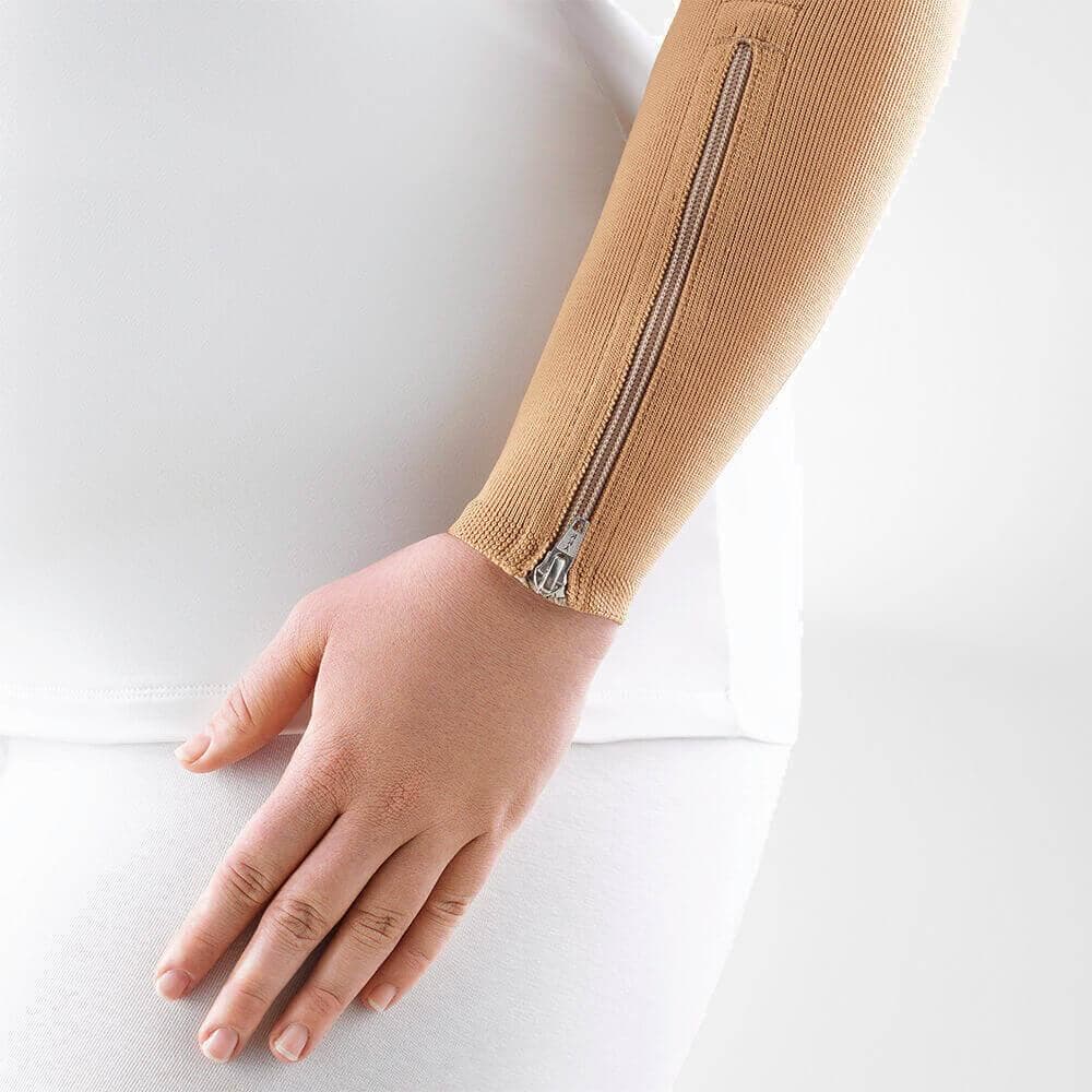 VenoTrain® curaflow armkousen 7 Damesarm met zilveren rits op een beige mouwen en witte top, focus op kleding en textuur voor gezondheids- en fitnesspraktijk FriskFysio.nl.