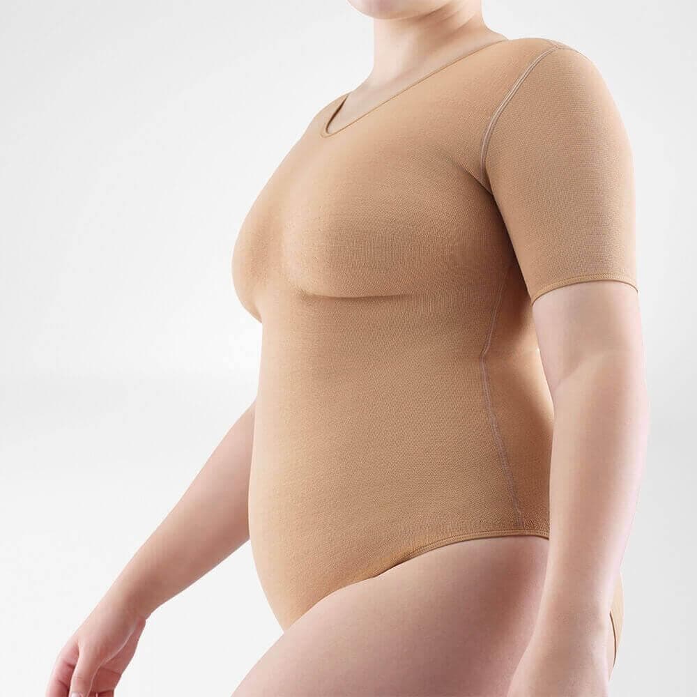 VenoTrain® curaflow thorax 3 Vrouw in beige shapewear bodysuit voor ondersteuning en comfort, zittend poseert vanuit zijaanzicht.