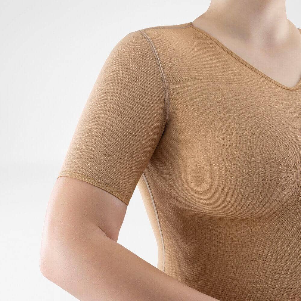 VenoTrain® curaflow thorax 1 Vrouwelijk sporttop driekwart zicht, huidtint kneeparm en schouders, beige-nude stretchkleding van FRISKFYSIO voor actieve fitness en therapeutsiche rehabilitatie.